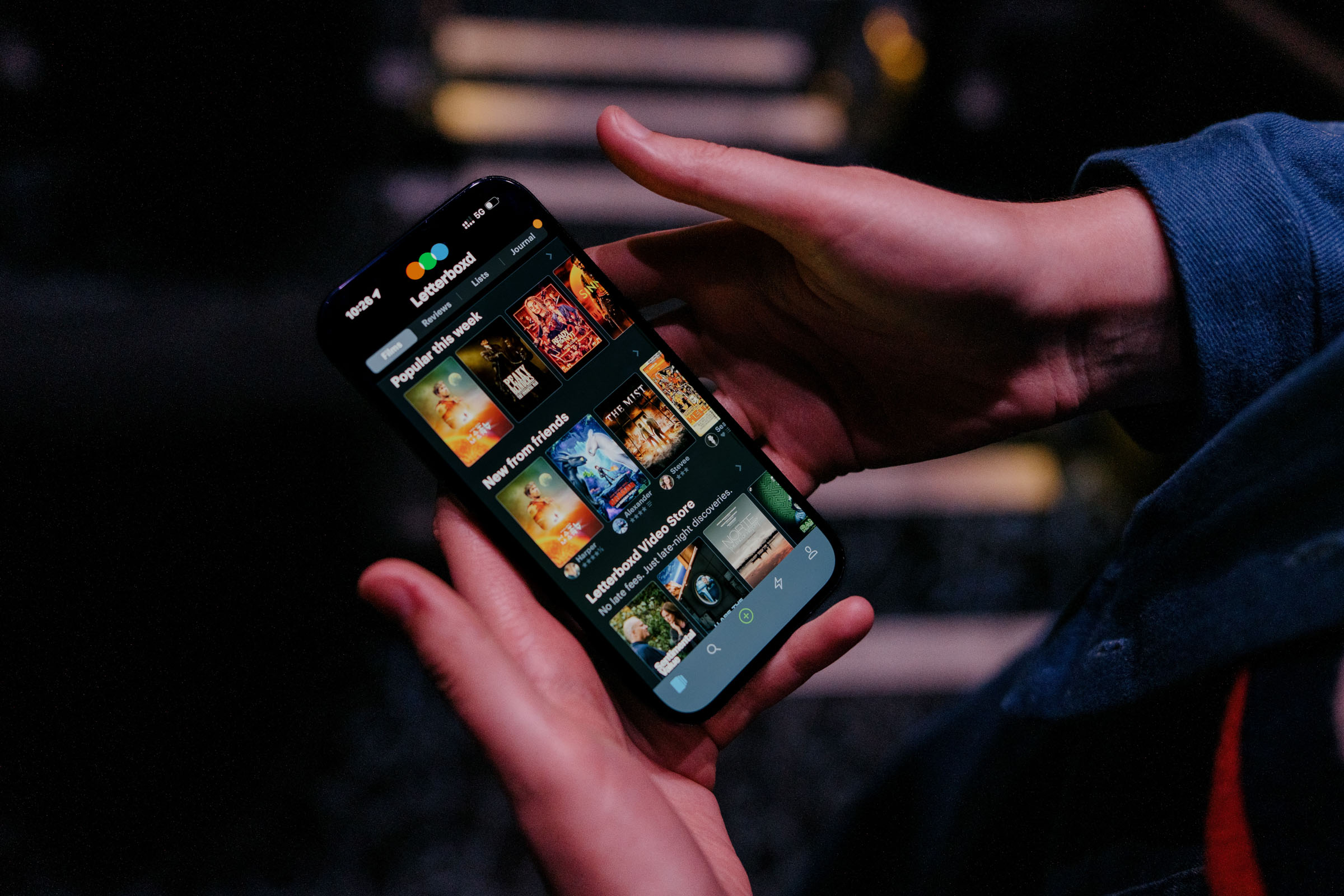 A person holds a phone displaying the Letterboxd app in a dark theater.