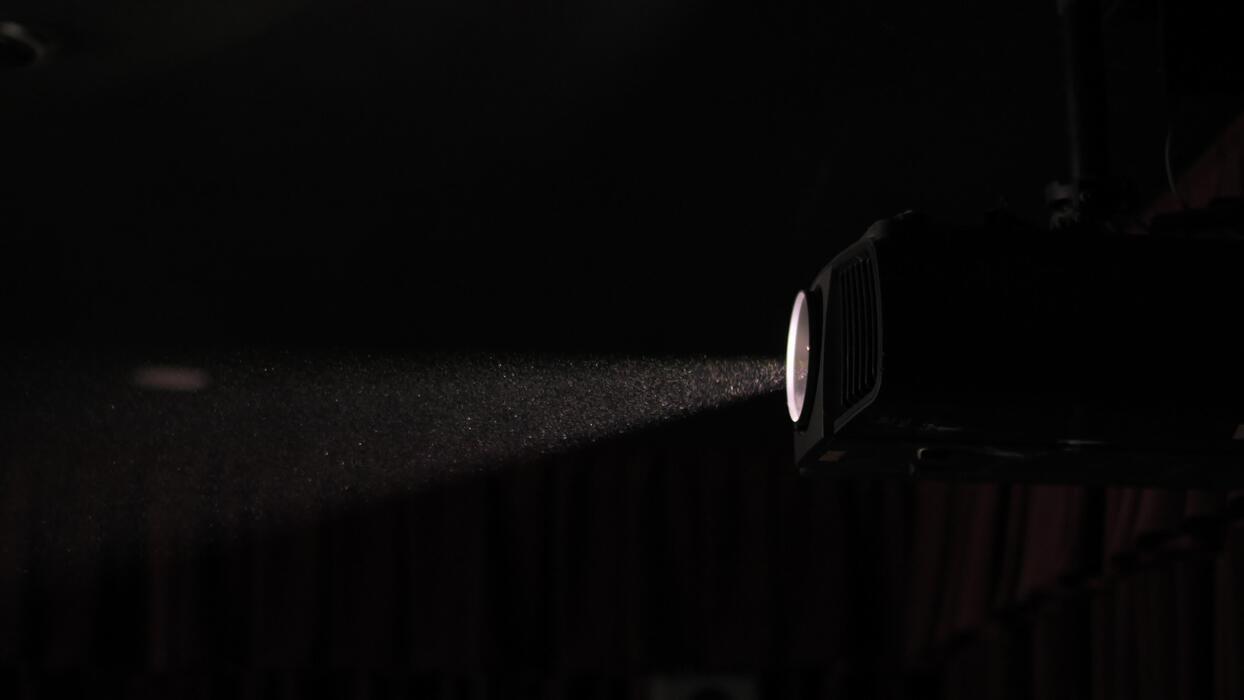 A cinema projector casts a visible beam of light through a dark theater.