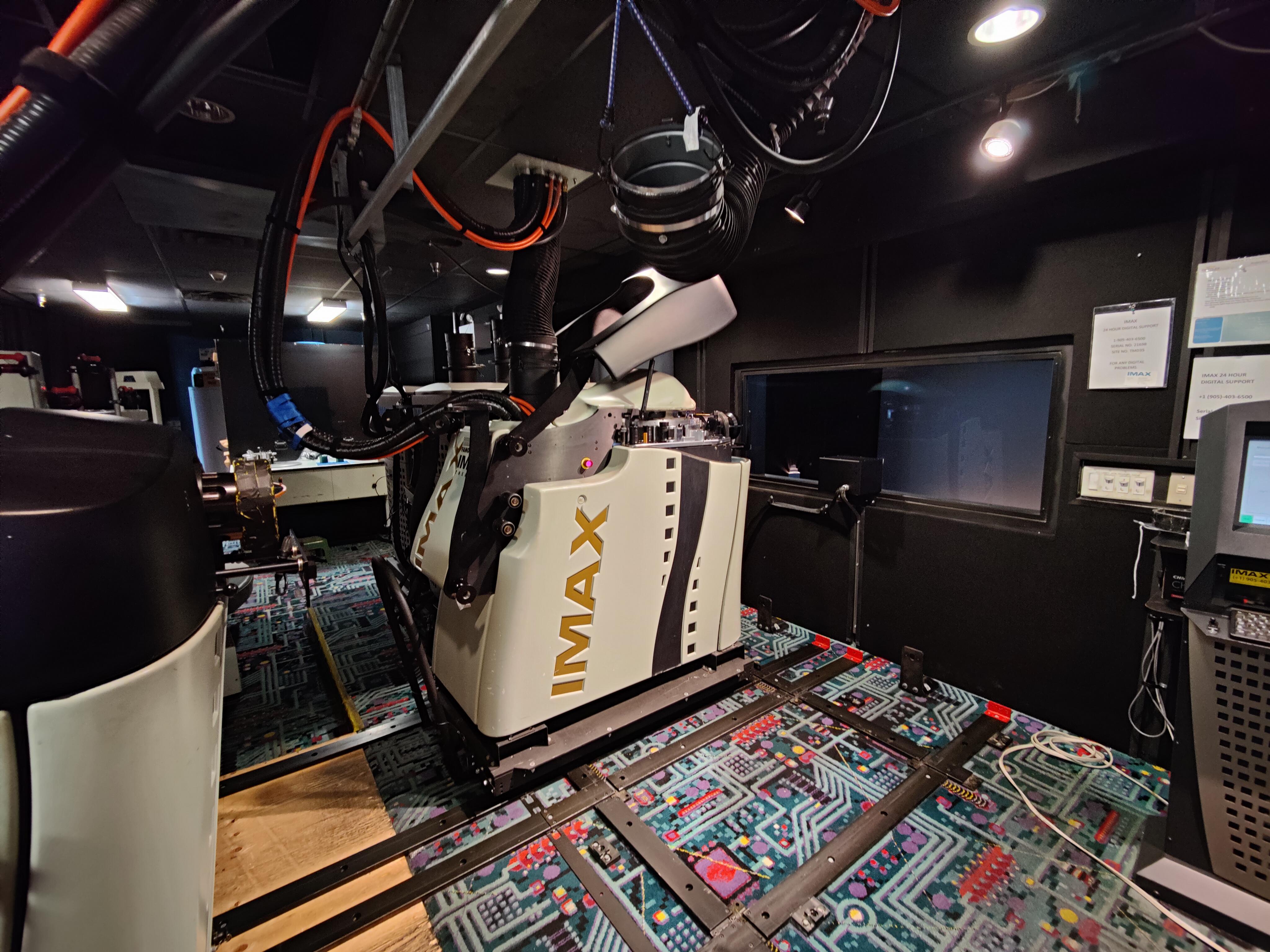 A large IMAX projection system inside a cinema projection booth.