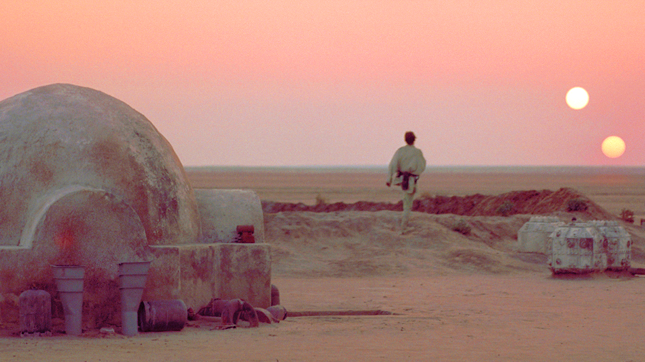 Luke Skywalker stands outside his home on Tatooine beneath the planet’s twin suns.