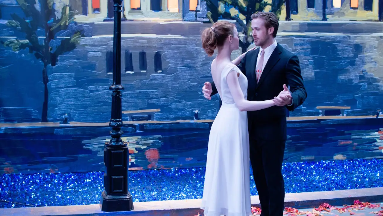 Mia and Sebastian dance together before a painted nighttime city backdrop during the film’s final fantasy sequence.