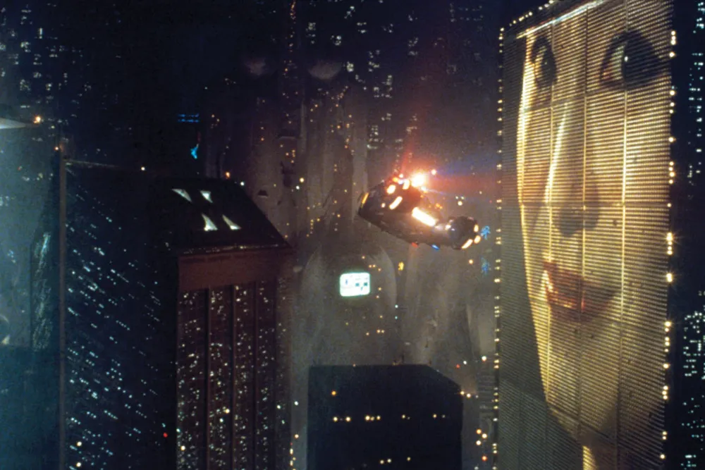 A police spinner flies through the dense illuminated skyline of Los Angeles in Blade Runner.