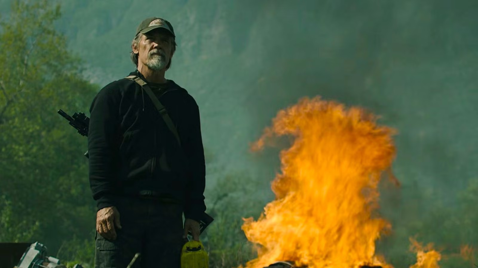 Josh Brolin stands beside a large fire in a mountain setting in The Dog Stars.