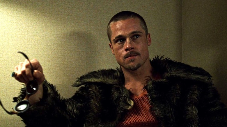 Brad Pitt as Tyler Durden sits in a dark fur coat in Fight Club.