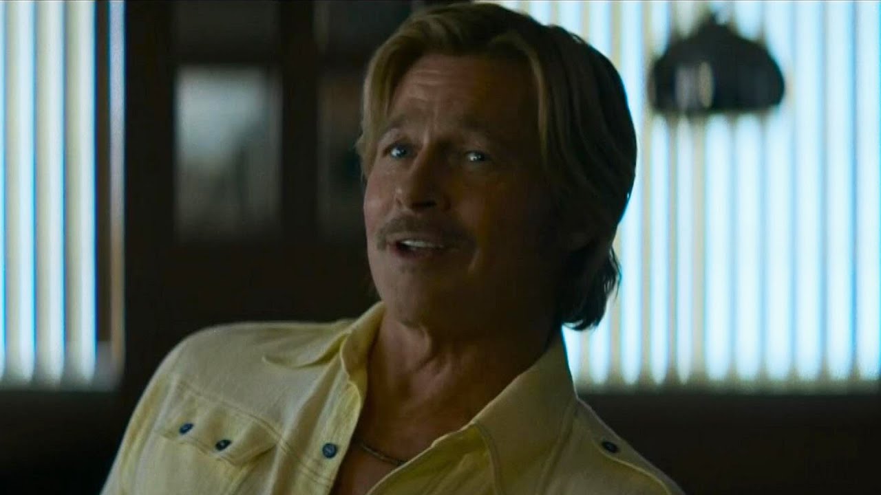 Brad Pitt as an older Cliff Booth speaks inside a dimly lit room in The Further Mis-Adventures of Cliff Booth.