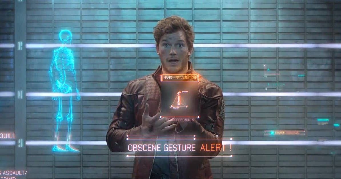 A science-fiction character stands before a holographic interface in a futuristic room.