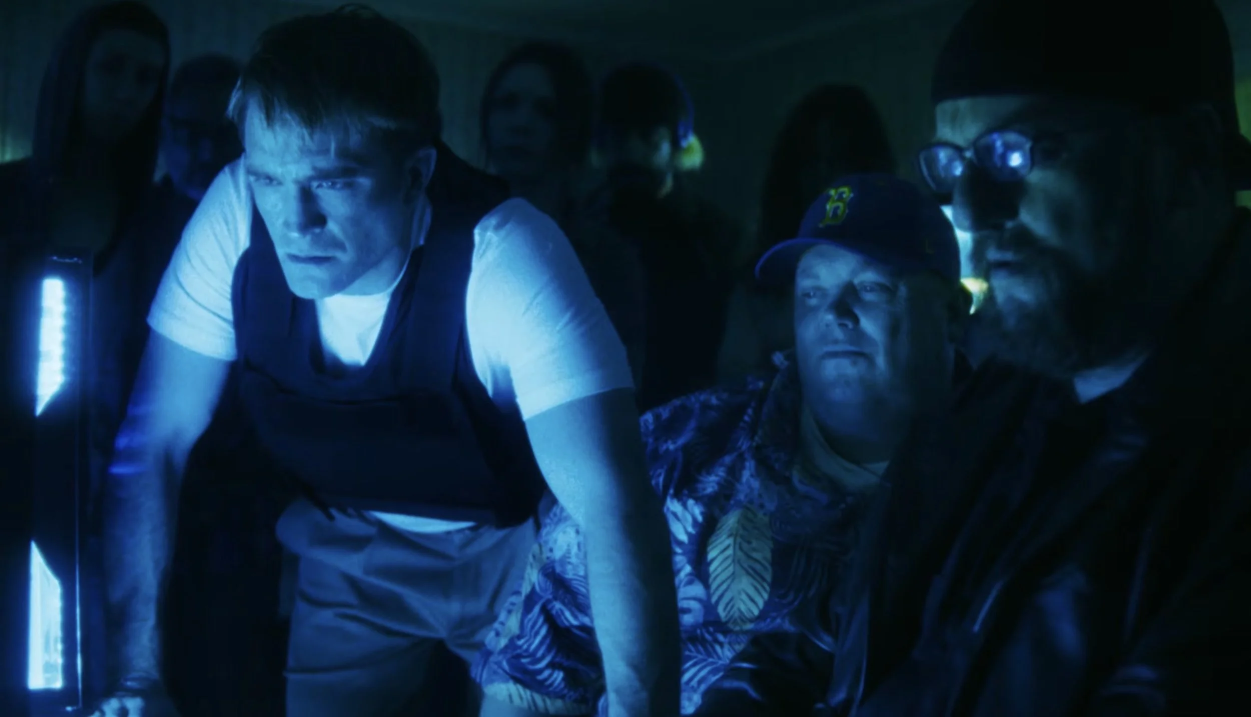 Robert Pattinson leans toward glowing monitors in a dark television control room in Primetime.