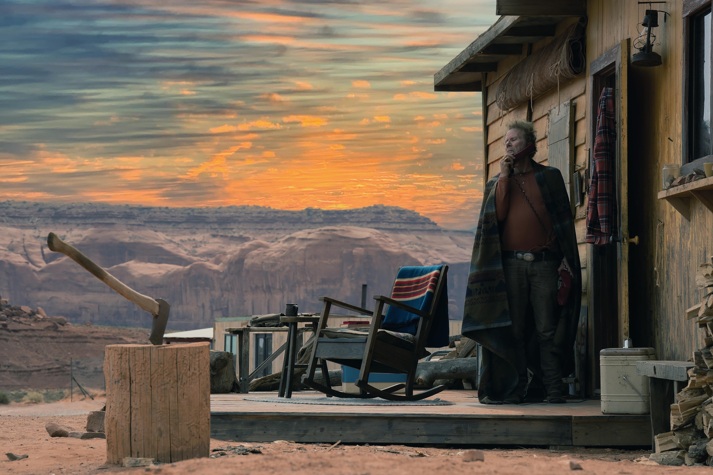 A man stands outside a remote wooden house beneath an orange sunset in Wild Horse Nine.