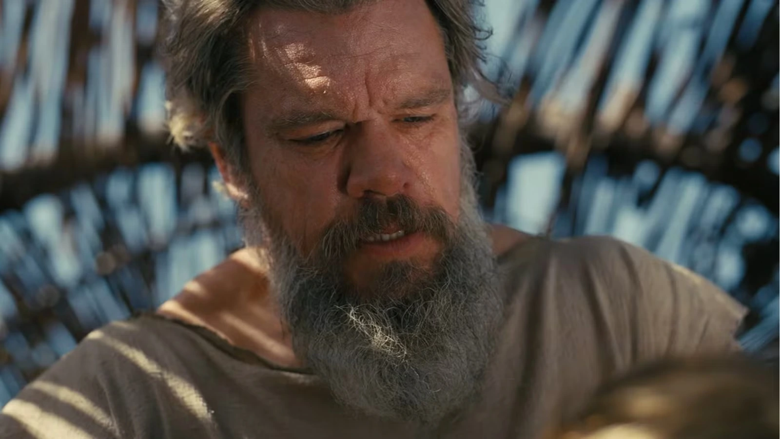 Matt Damon appears weathered and bearded beneath a wooden structure in The Odyssey.