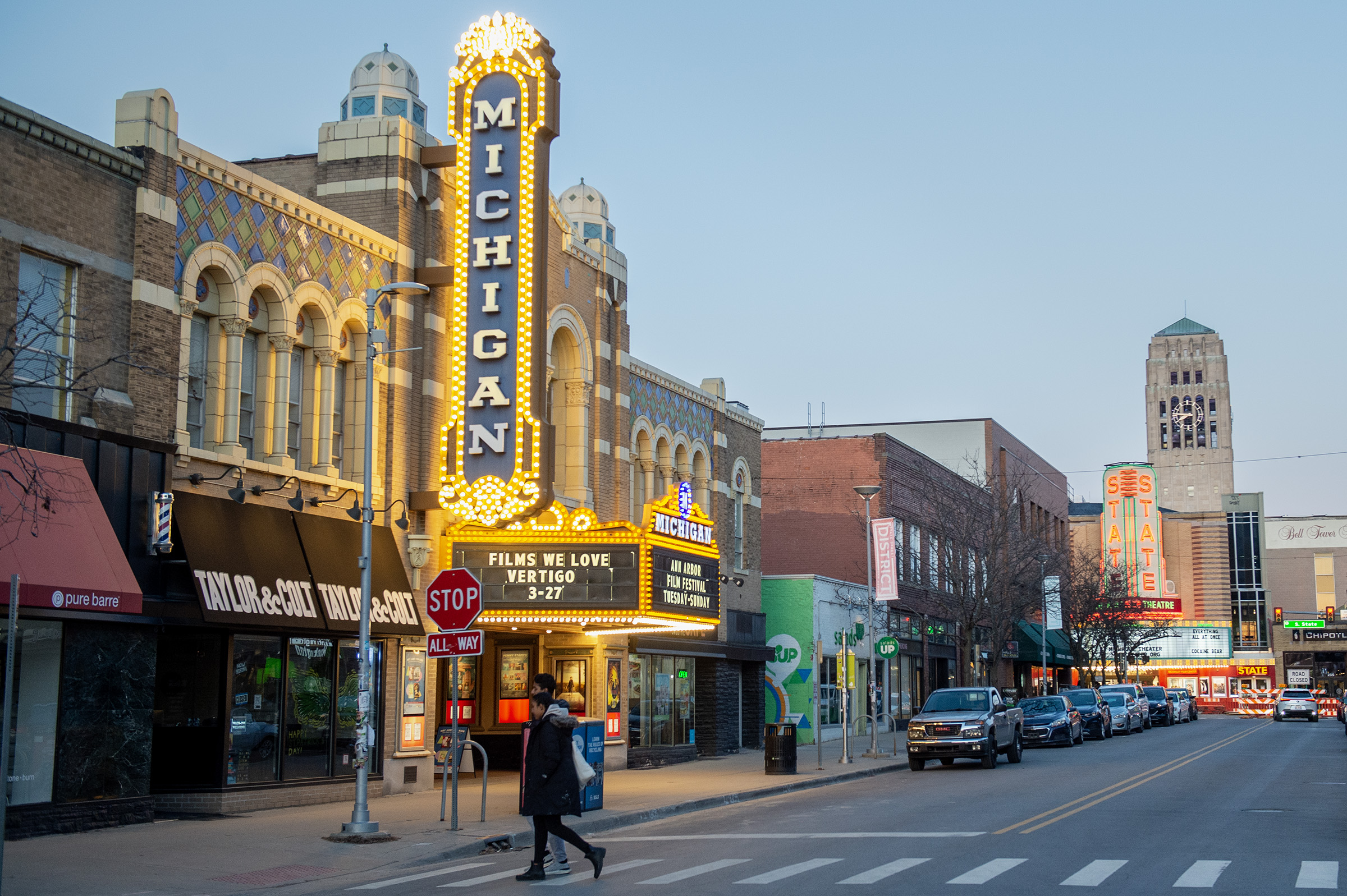 The Michigan Theater and State Theatre marquees glow along a street in downtown Ann Arbor.