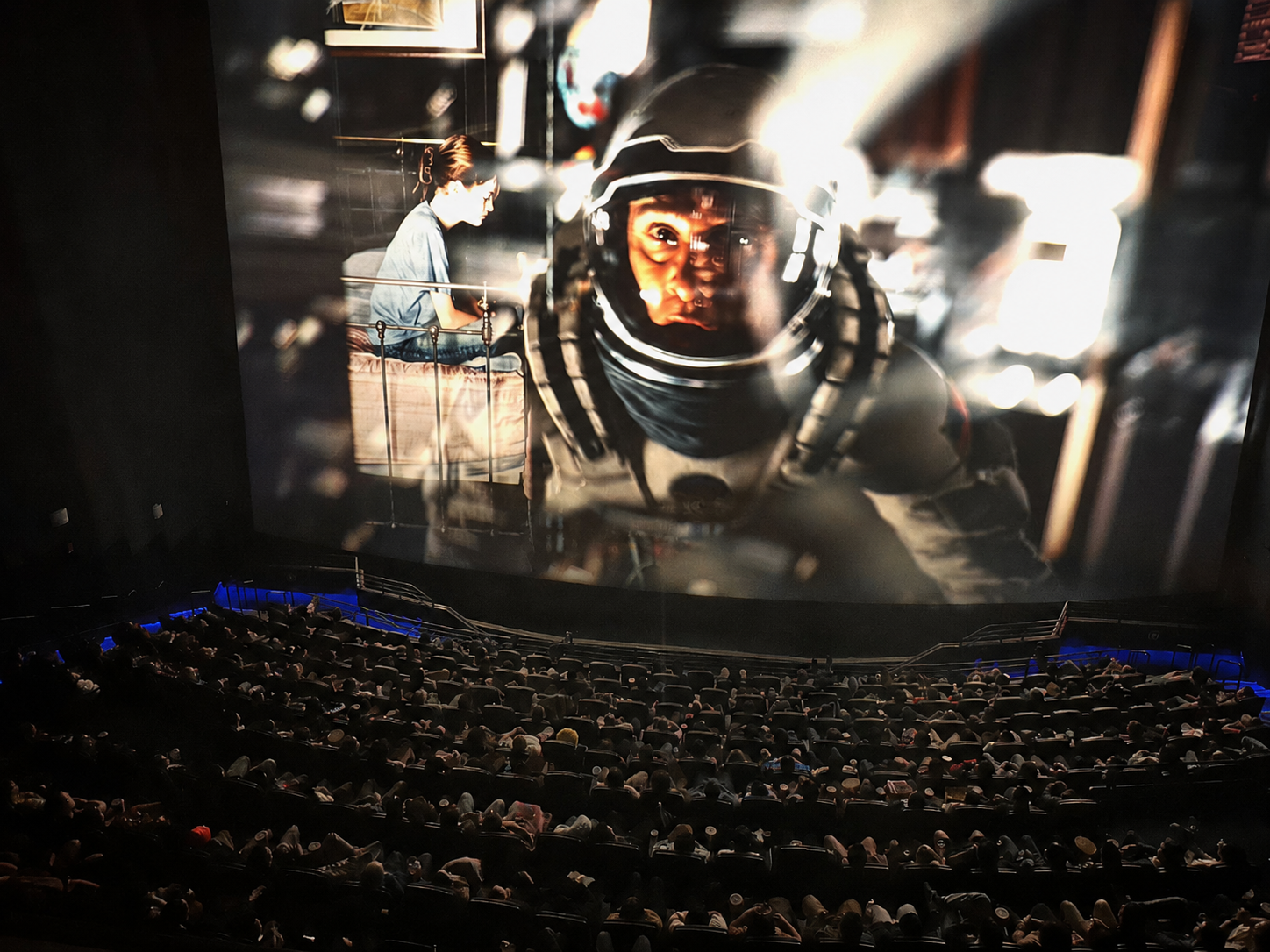 A large cinema audience watches Interstellar on a giant movie screen.