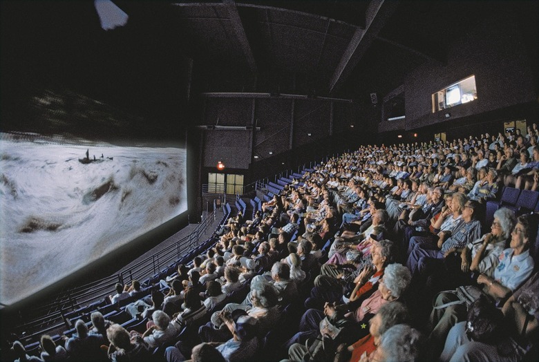 A packed movie theater audience faces a large screen.