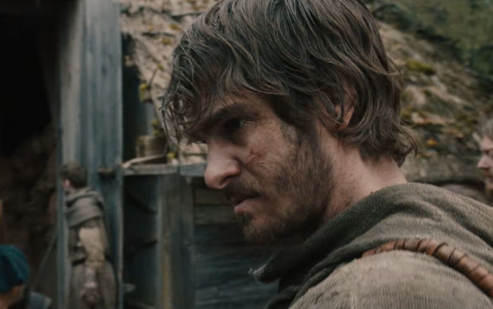 A dirt-covered Andrew Garfield looks to the side in a close-up from The Uprising.
