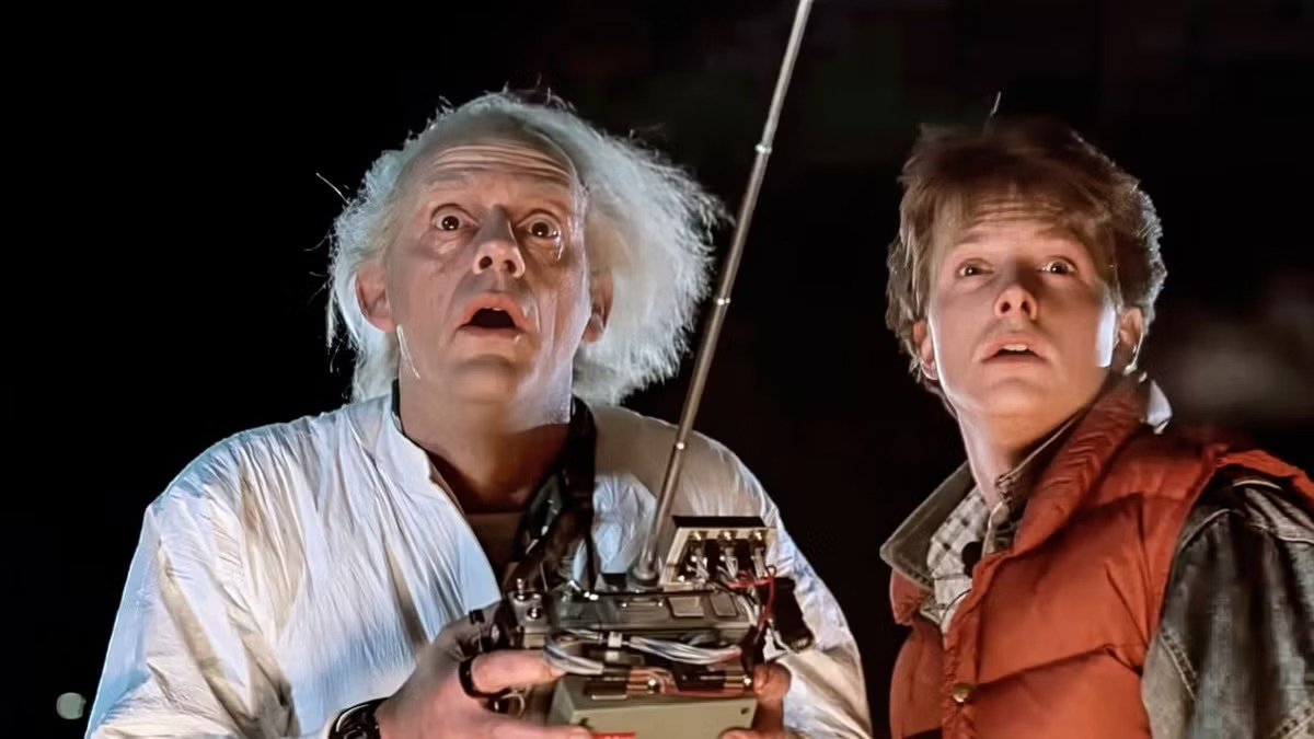 Doc Brown and Marty McFly look upward while holding a remote control in Back to the Future.