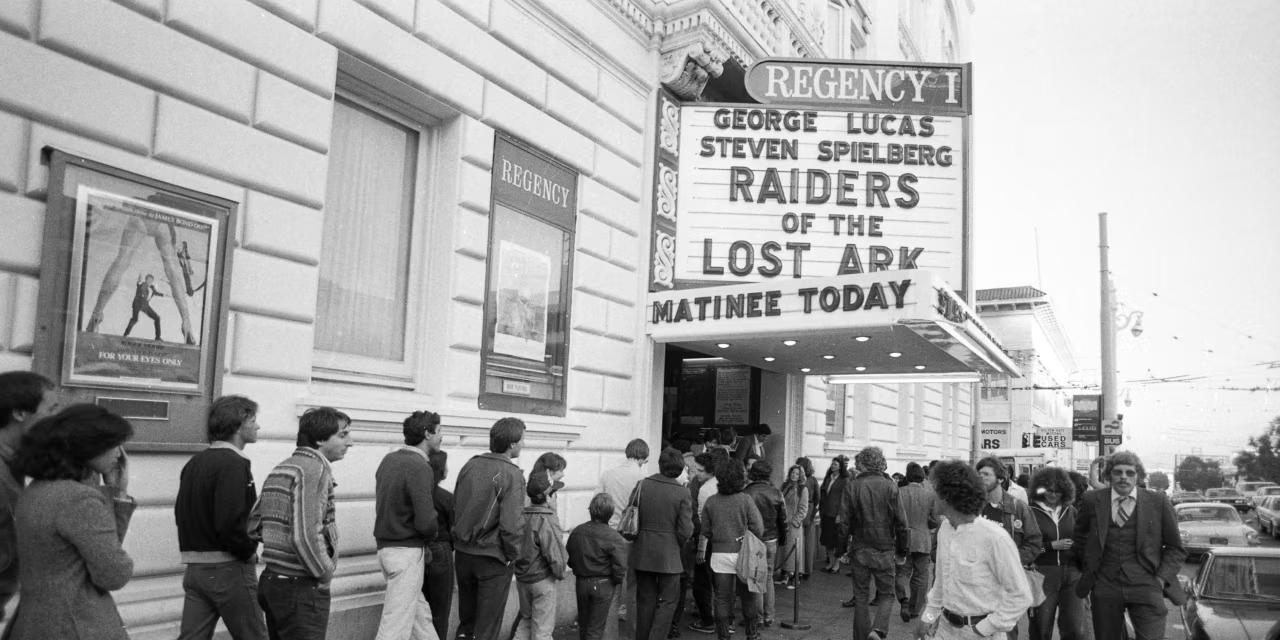 Moviegoers line up outside a theater marquee advertising Raiders of the Lost Ark.