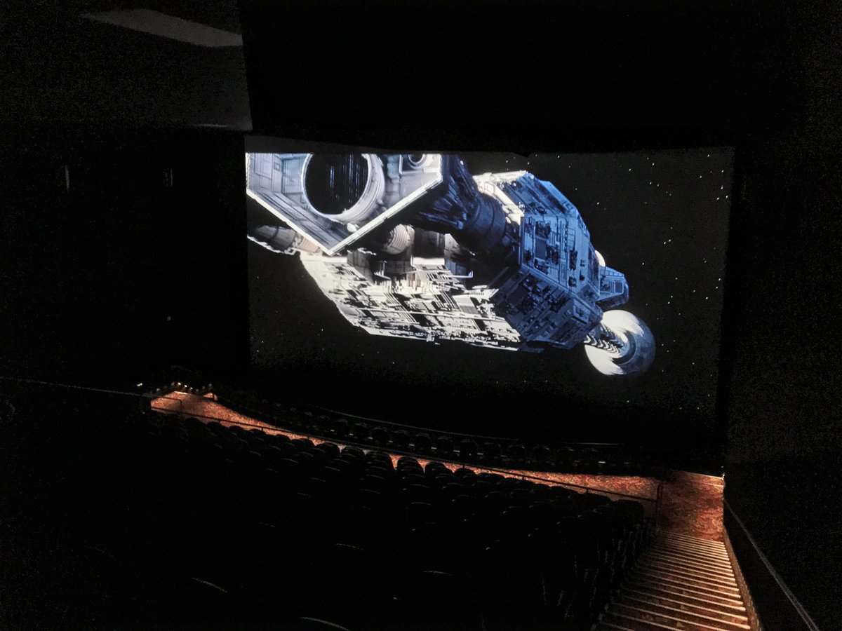 A dark movie theater displays a spacecraft from Interstellar on a very large screen.