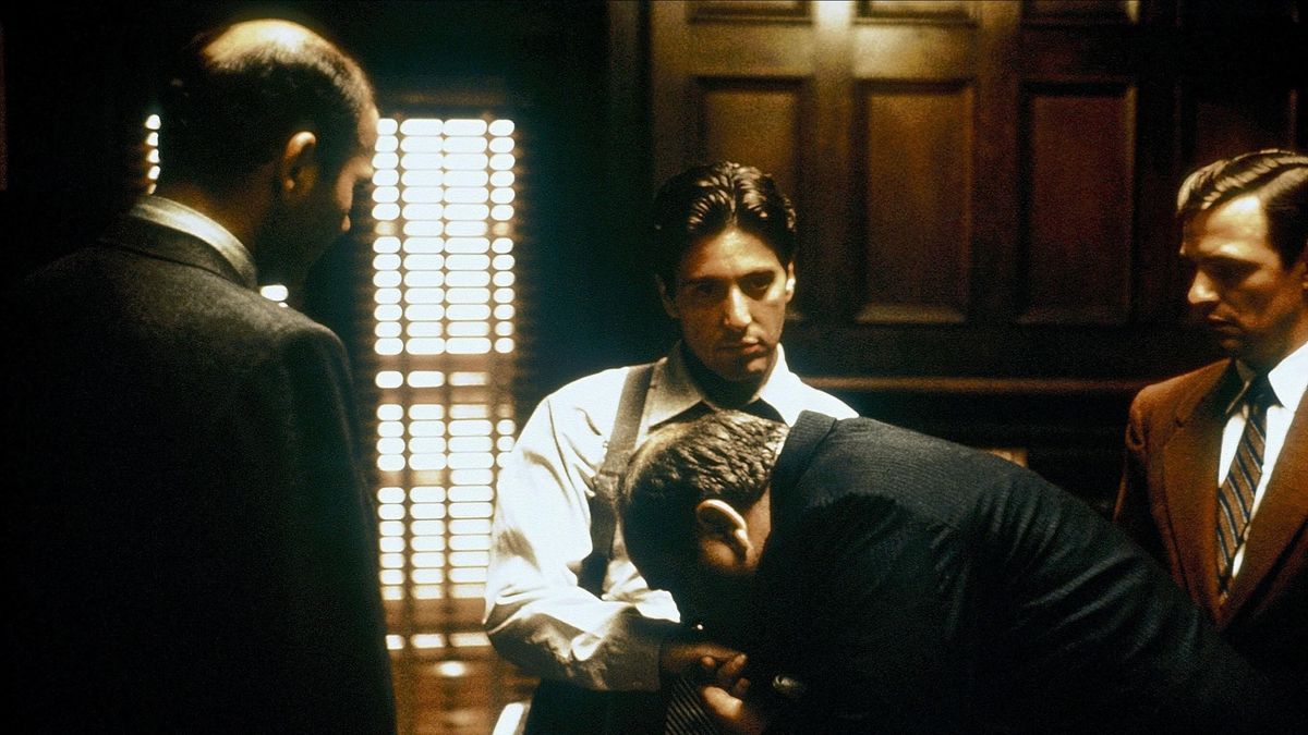 Michael Corleone stands in his office as men gather around him in The Godfather.