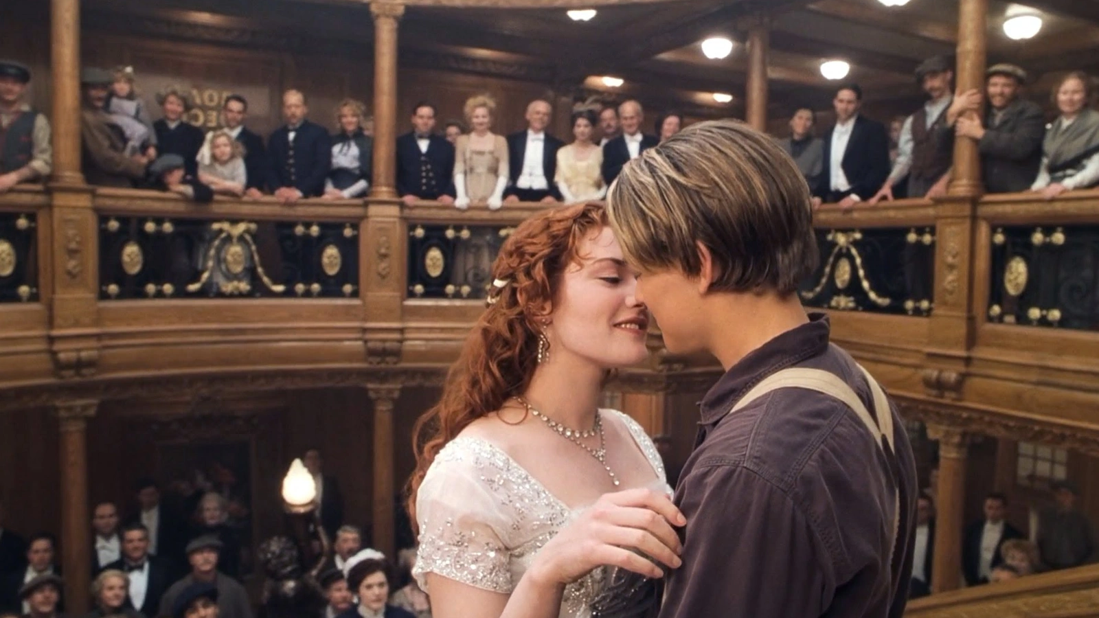 Jack and Rose stand close together inside the grand staircase area of Titanic.