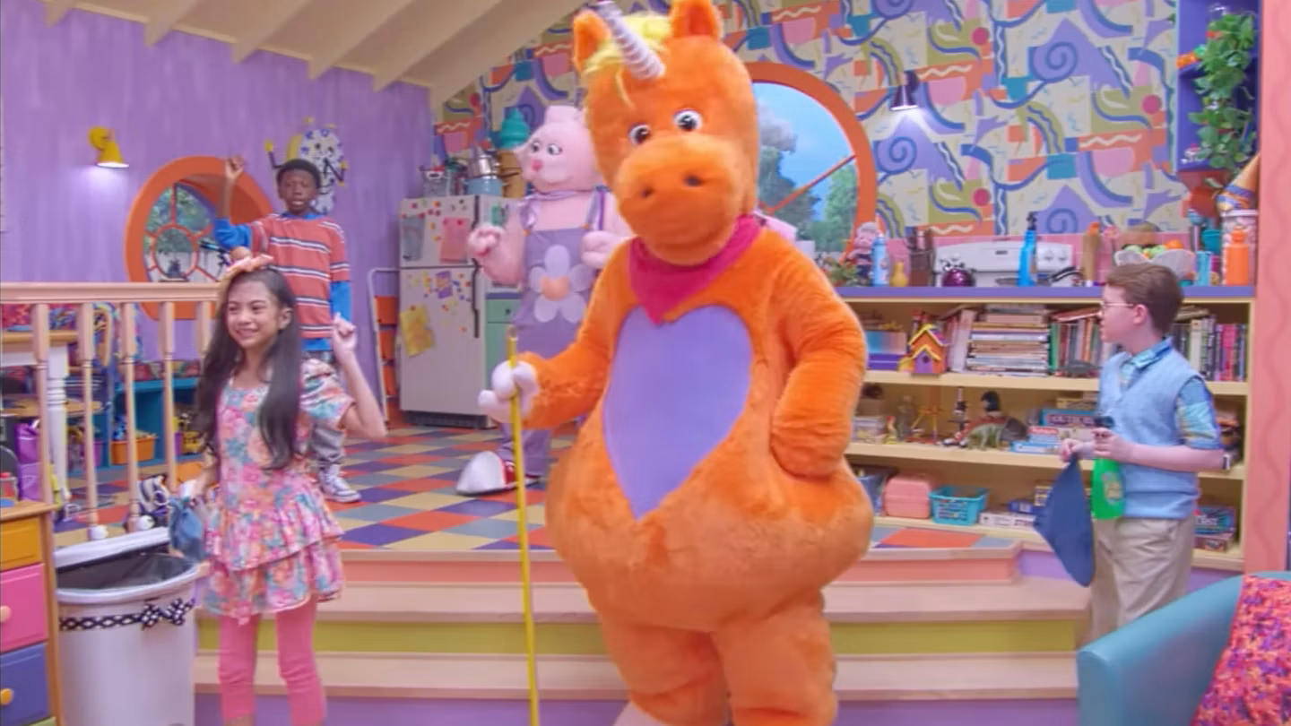 Buddy stands with children inside the brightly colored set of the fictional television show It’s Buddy!
