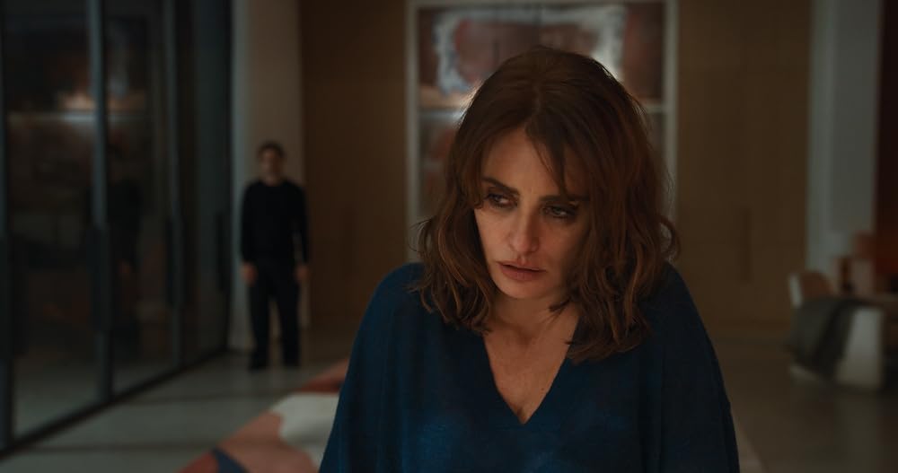 Penélope Cruz sits inside a modern home, looking exhausted and emotionally distant.