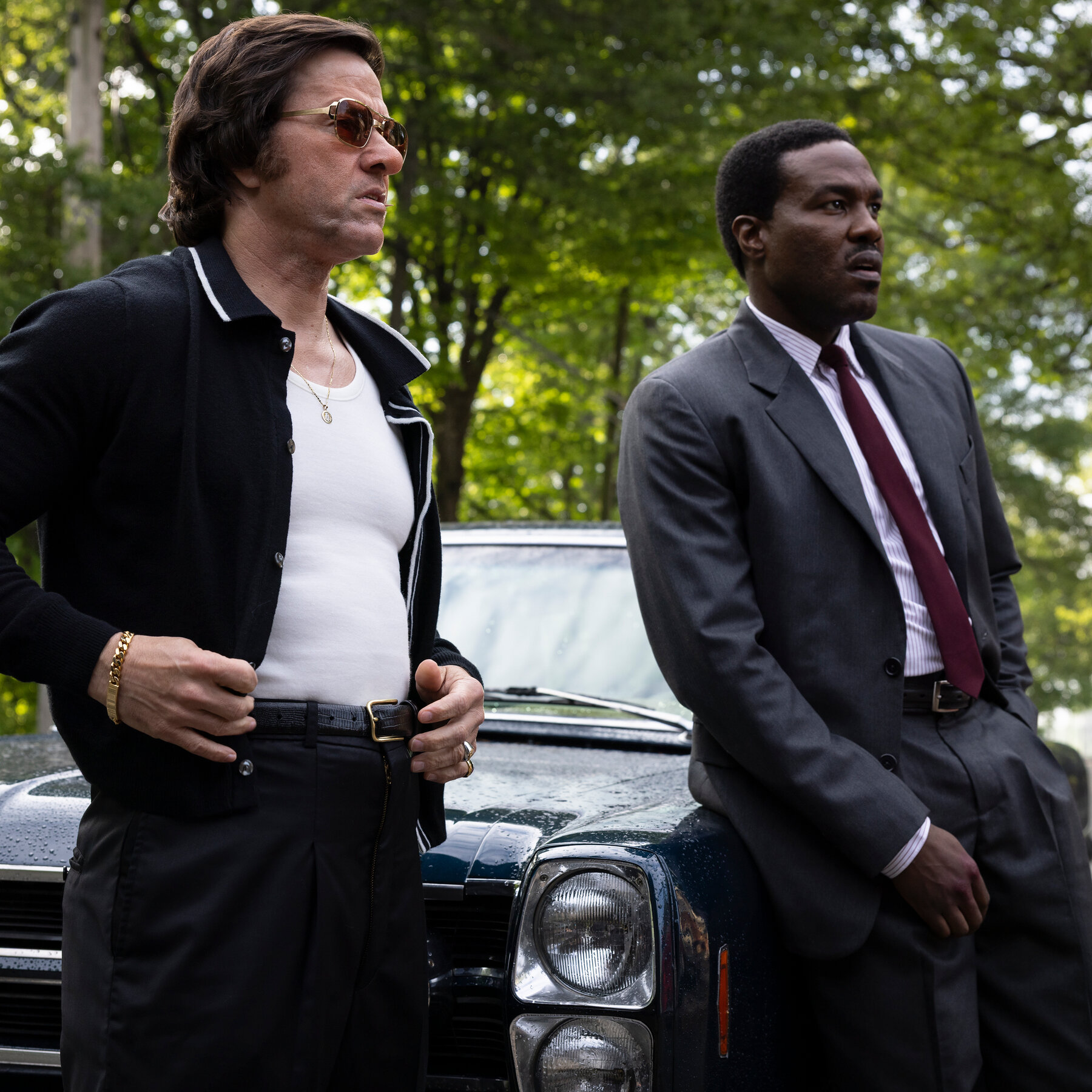 Mark Wahlberg and Yahya Abdul-Mateen II stand beside a vintage car outdoors.