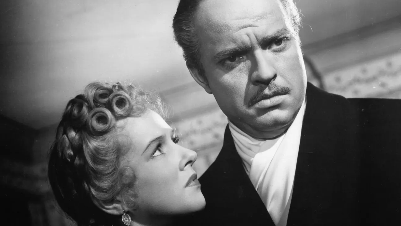 Dorothy Comingore looks up at Orson Welles as Charles Foster Kane in a black-and-white scene from Citizen Kane.