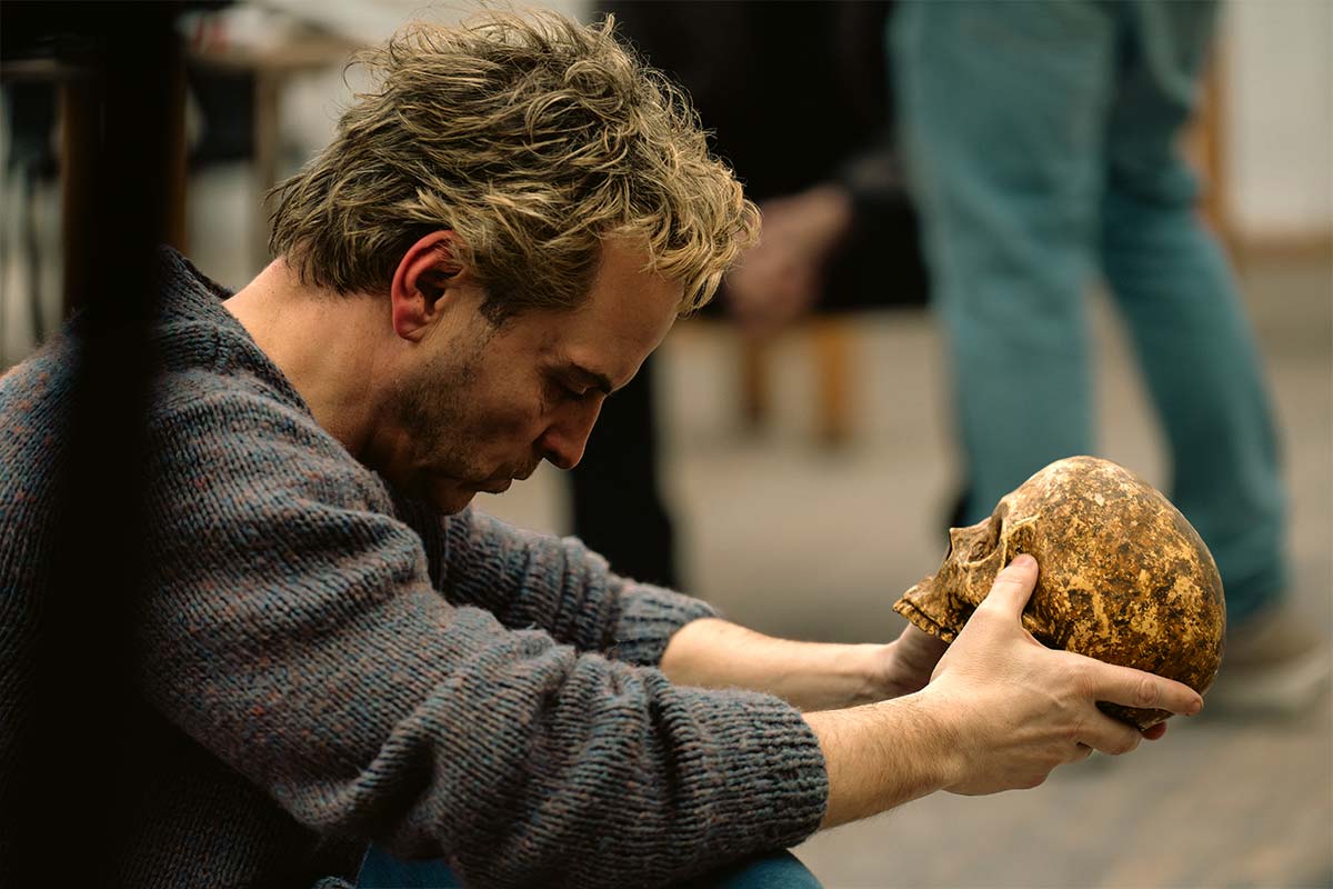Andrew Scott sits backstage holding a human skull in both hands