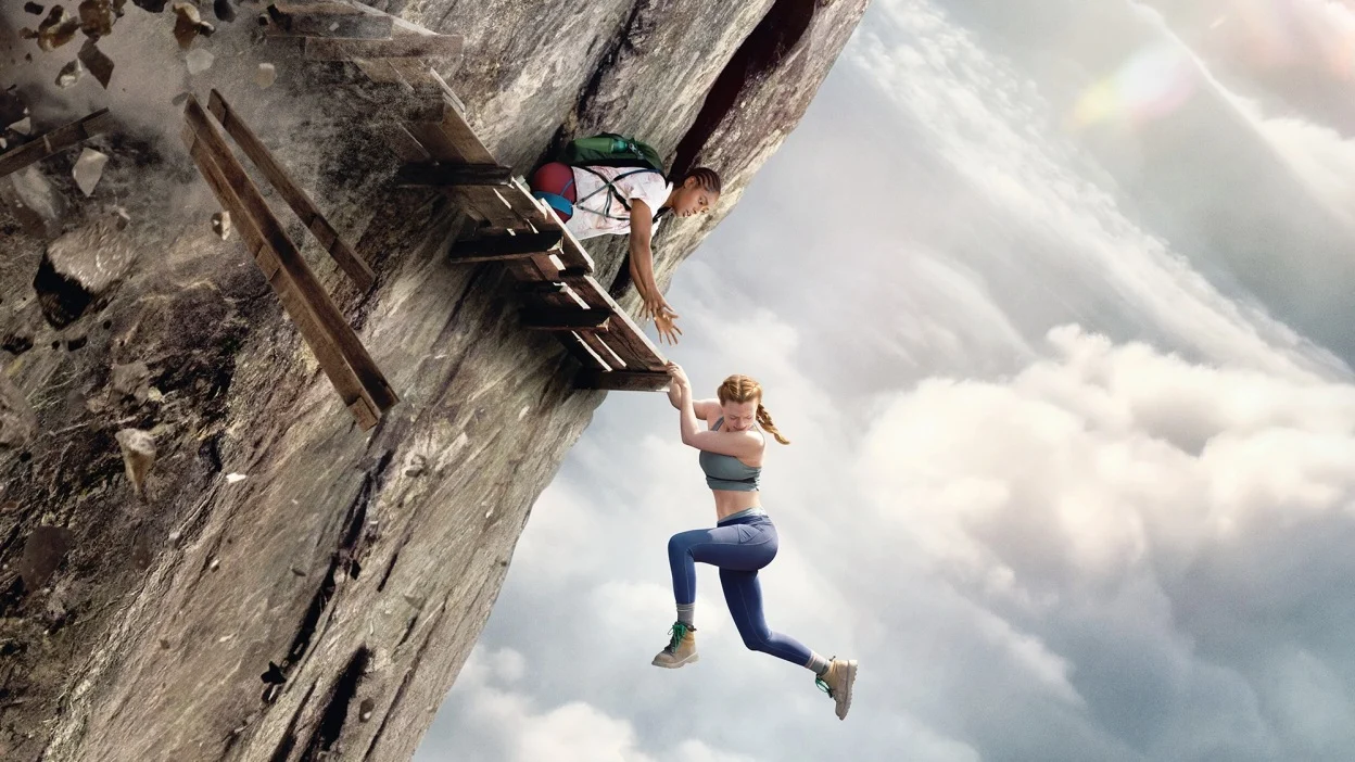 Two climbers cling to a broken wooden structure attached to a steep cliff above the clouds.
