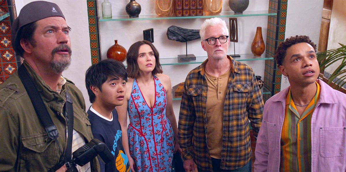 Ken Marino, Ben Wang, Miles Gutierrez-Riley, John Slattery and Zoey Deutch look upward together inside a brightly decorated room.