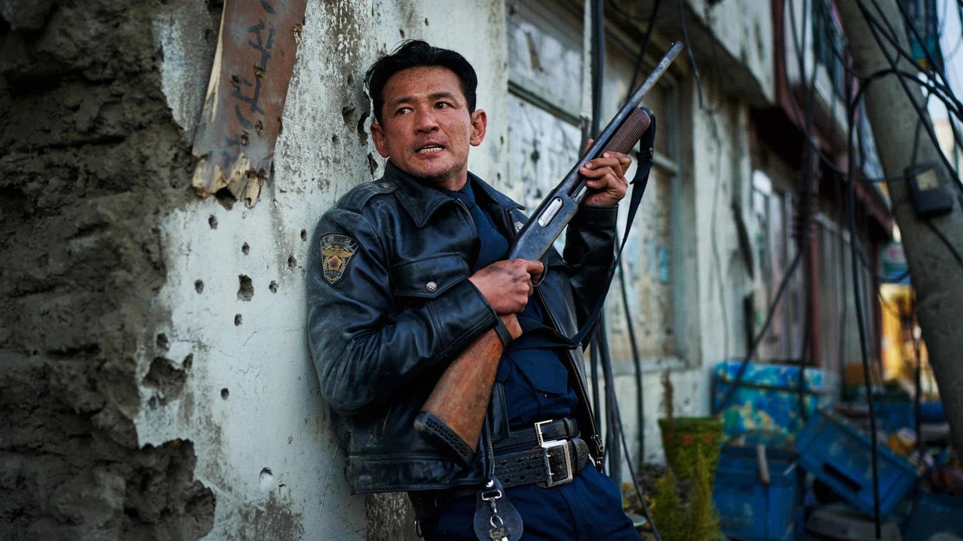 Hwang Jung-min holds a shotgun while taking cover against a damaged wall in Hope.