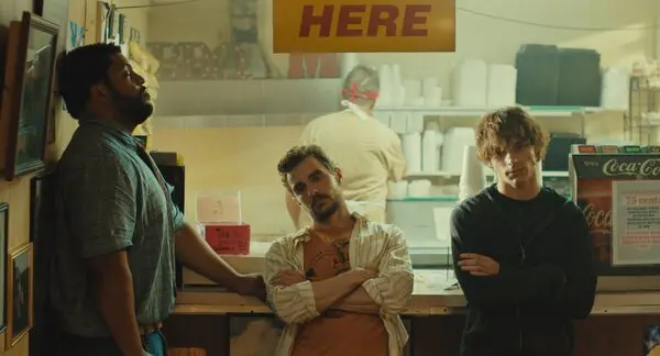 O’Shea Jackson Jr., Dave Franco, and Mason Thames stand inside a worn neighborhood restaurant in Idiots.