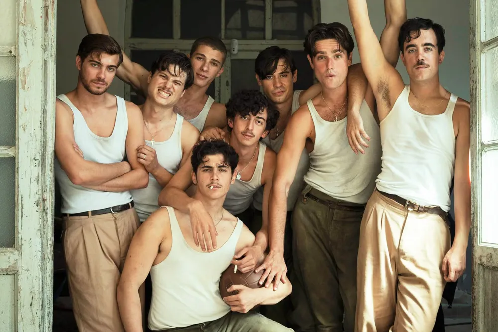 A group of young men in white undershirts gather closely together in a doorway.