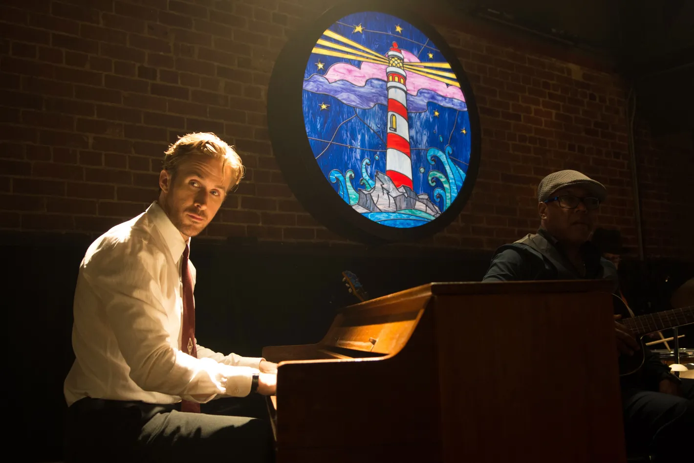 Ryan Gosling sits at a piano inside a dim jazz club in La La Land.