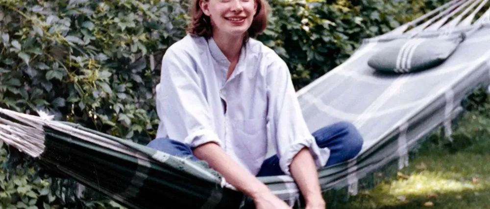 A young Mary Oliver relaxing outdoors with a book