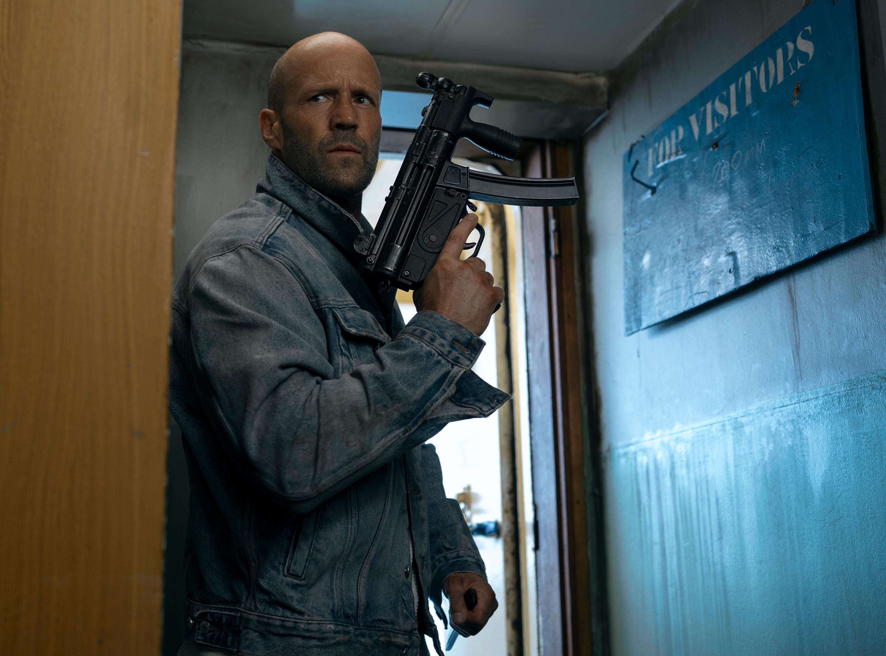 Jason Statham holds a compact firearm while standing in a narrow doorway in Mutiny.
