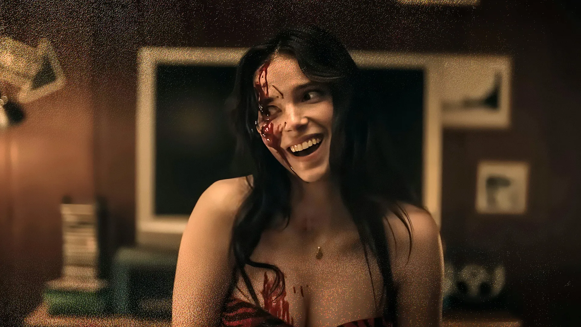 A young woman smiles widely, her face and dress streaked with blood.