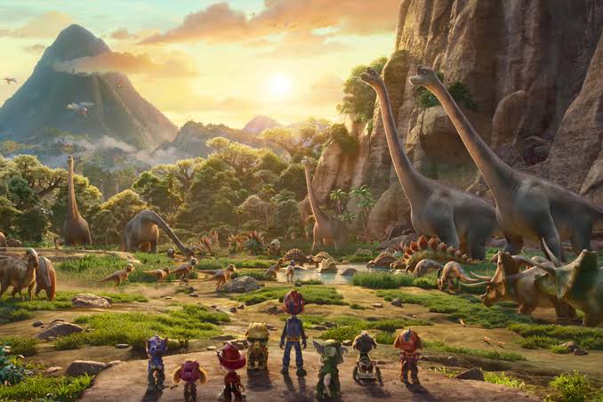 The PAW Patrol team looks across a lush valley filled with dinosaurs in PAW Patrol: The Dino Movie.