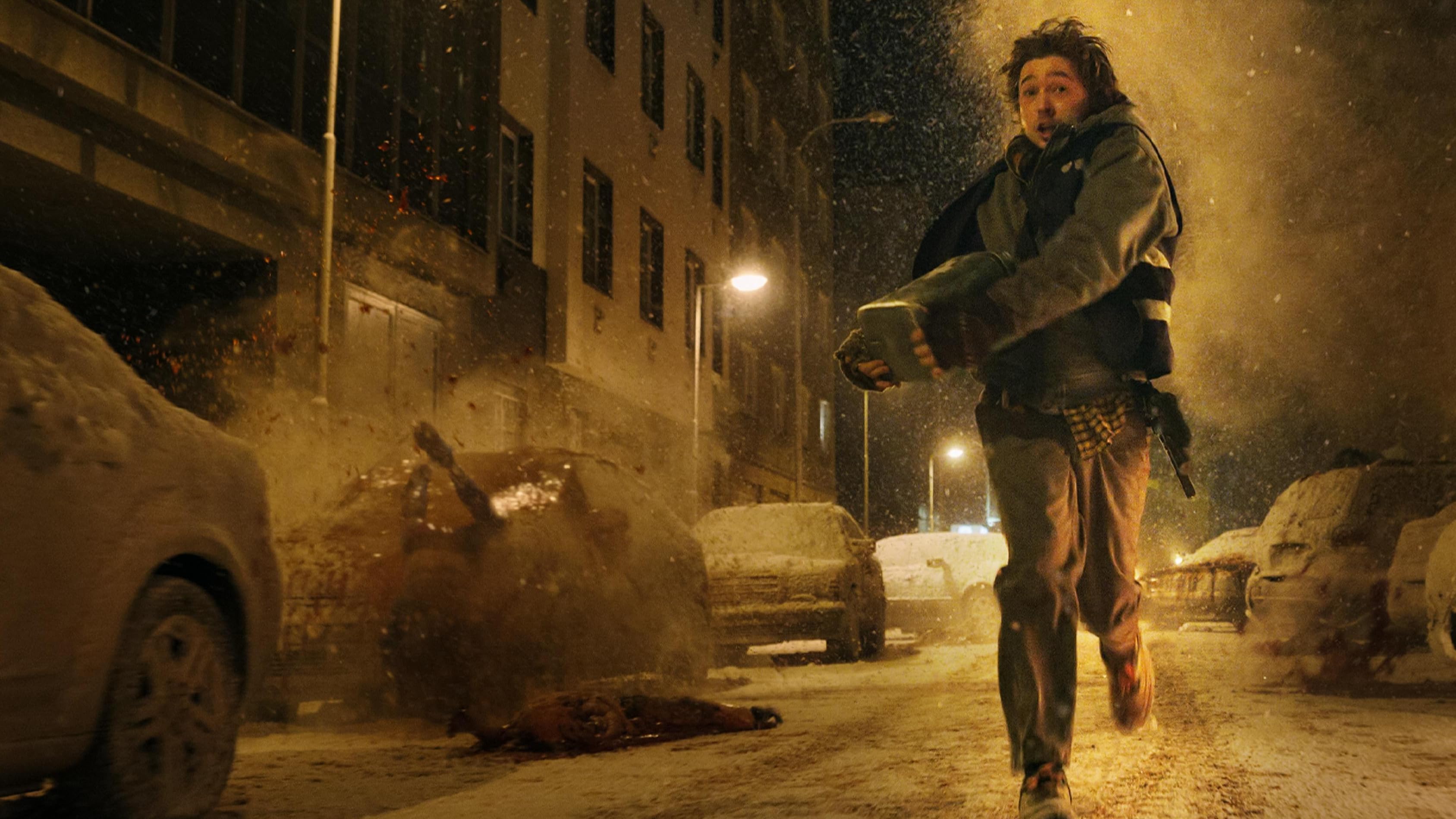 Austin Abrams runs down a snowy street at night as fire and debris erupt behind him.