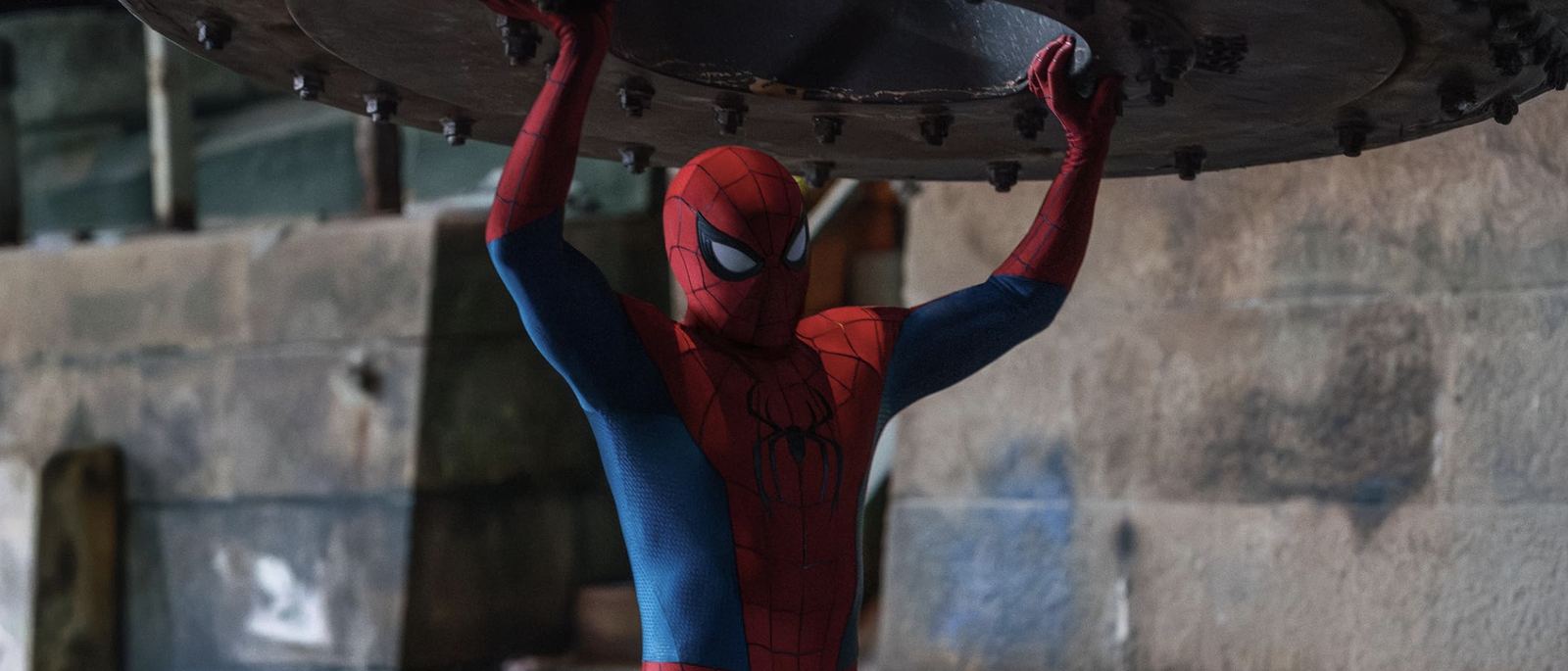 Spider-Man lifting a heavy industrial disc overhead