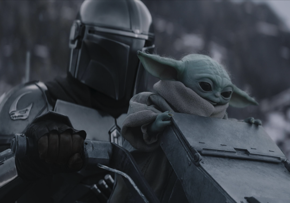 Din Djarin rides with Grogu perched beside him on a speeder.