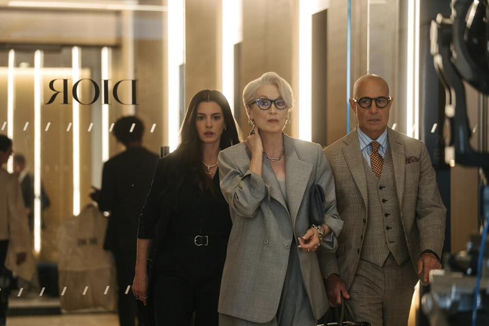 Miranda Priestly walks through a luxury store flanked by two colleagues.
