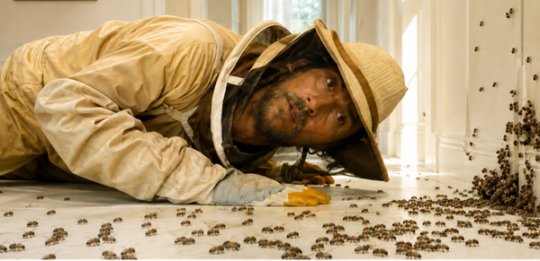 A beekeeper lies on the floor near a large cluster of bees in The Rivals of Amziah King.