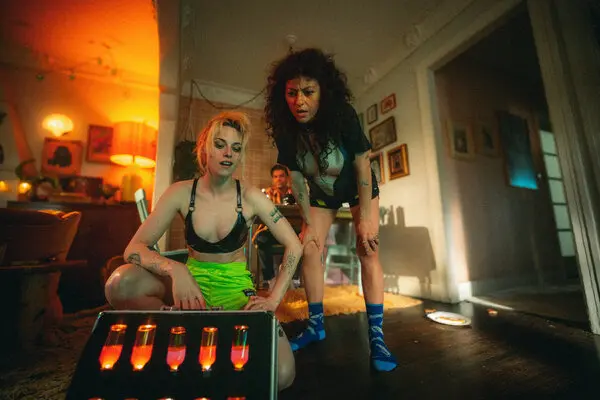 Kristen Stewart and Alia Shawkat look down at a case containing glowing vials in The Wrong Girls.