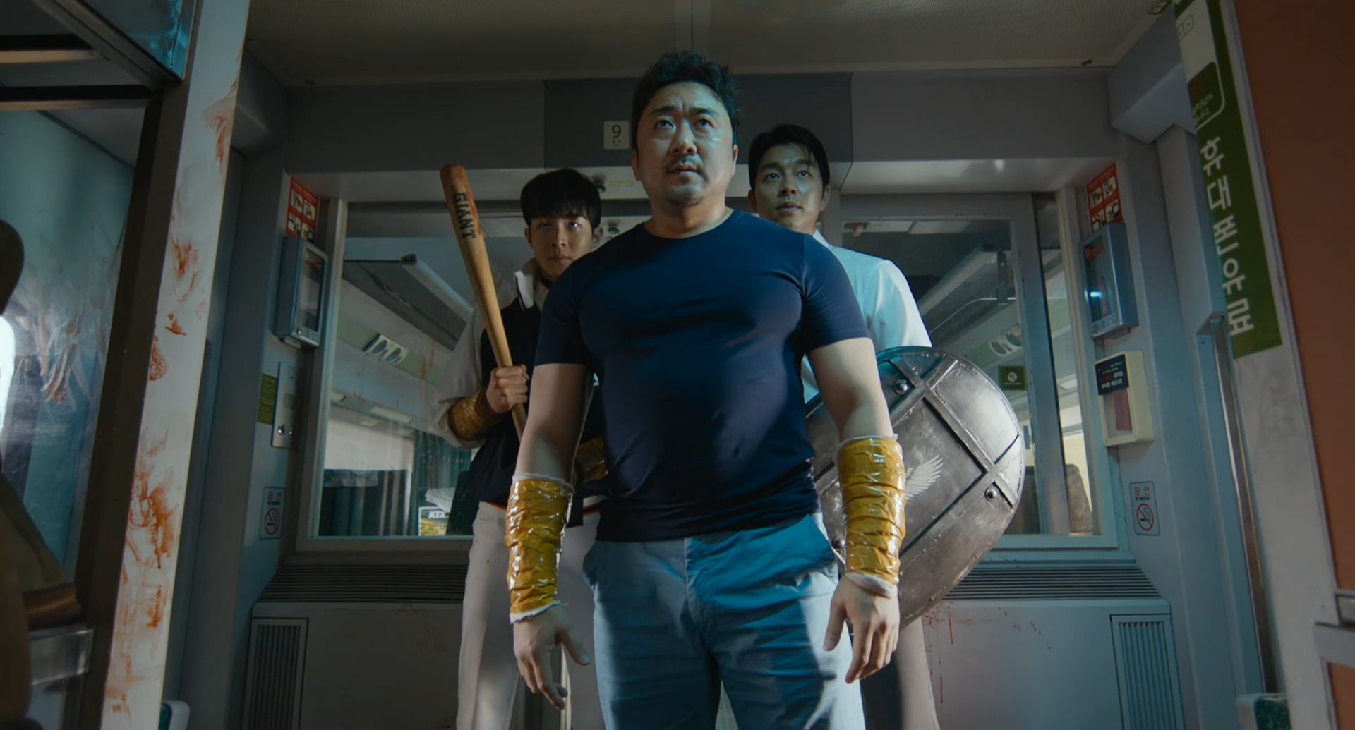 Ma Dong-seok stands at the front of a group of survivors inside a blood-streaked train car in Train to Busan.